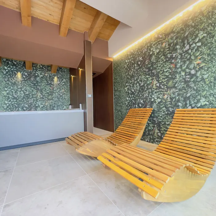 area wellness con due lettini in legno, parete di verde verticale e bancone bianco